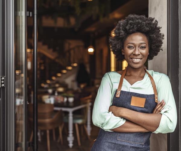 Café owner standing at the door with her arms crossed.