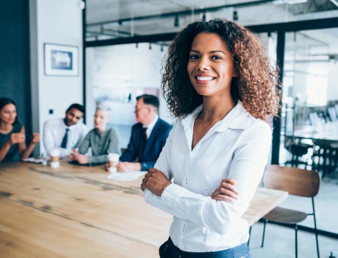 Businesswoman standing in conference room with her colleagues in the background 